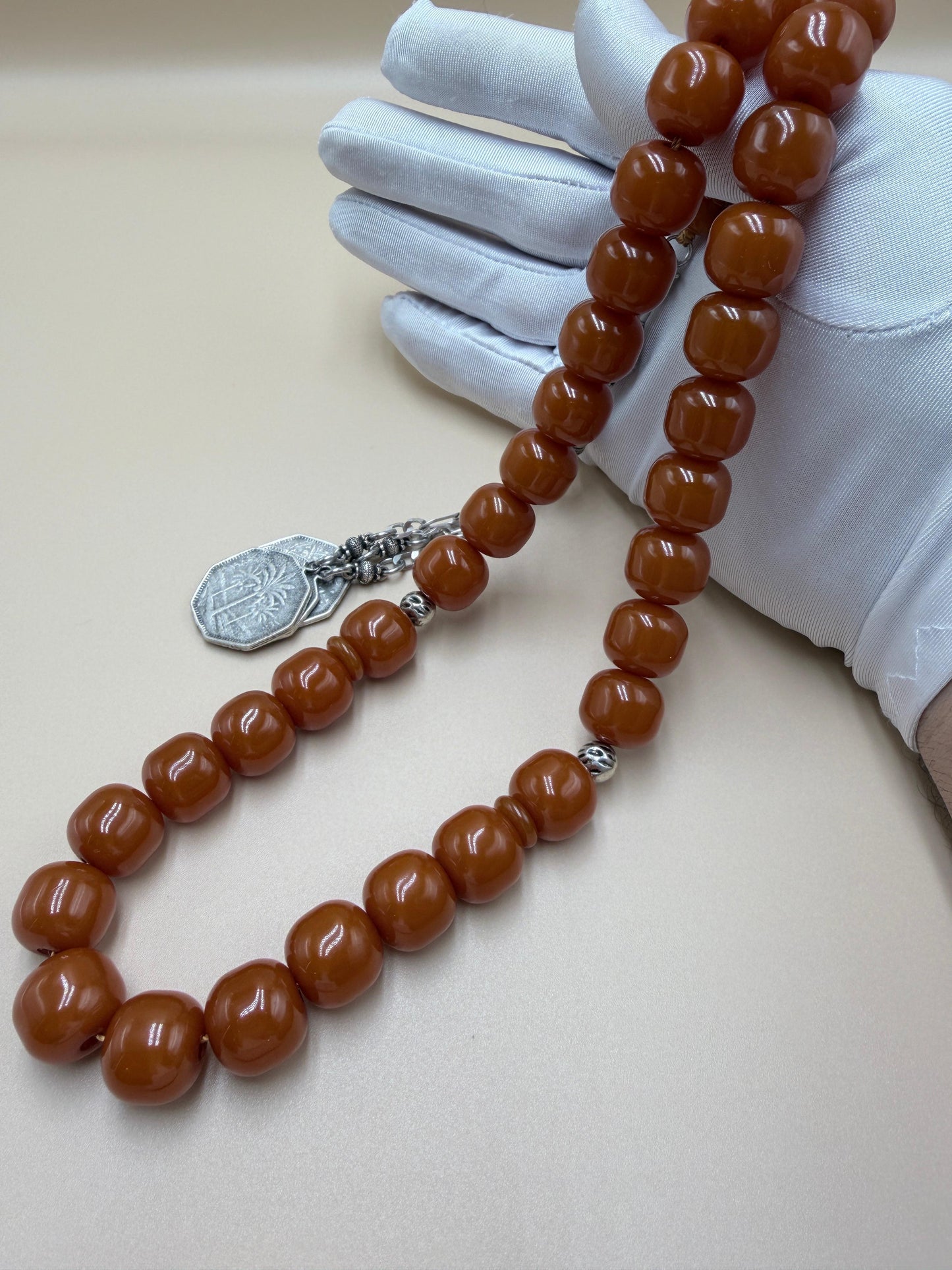 مسباح مسكي قديم، عرق أحمر، مع شرابة مميزة مزخرفة بالعملة العراقية القديمة وشرابة فضة عيار 500.