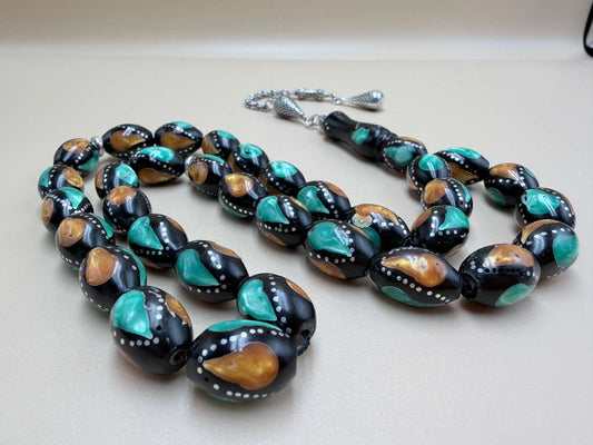 مسباح كوك، مطعّم بطحين الكهرمان وحجر المالاكيت والفضة. Kuka Wood Misbah, Inlaid with Amber Powder, Malachite Stone, and Silver.