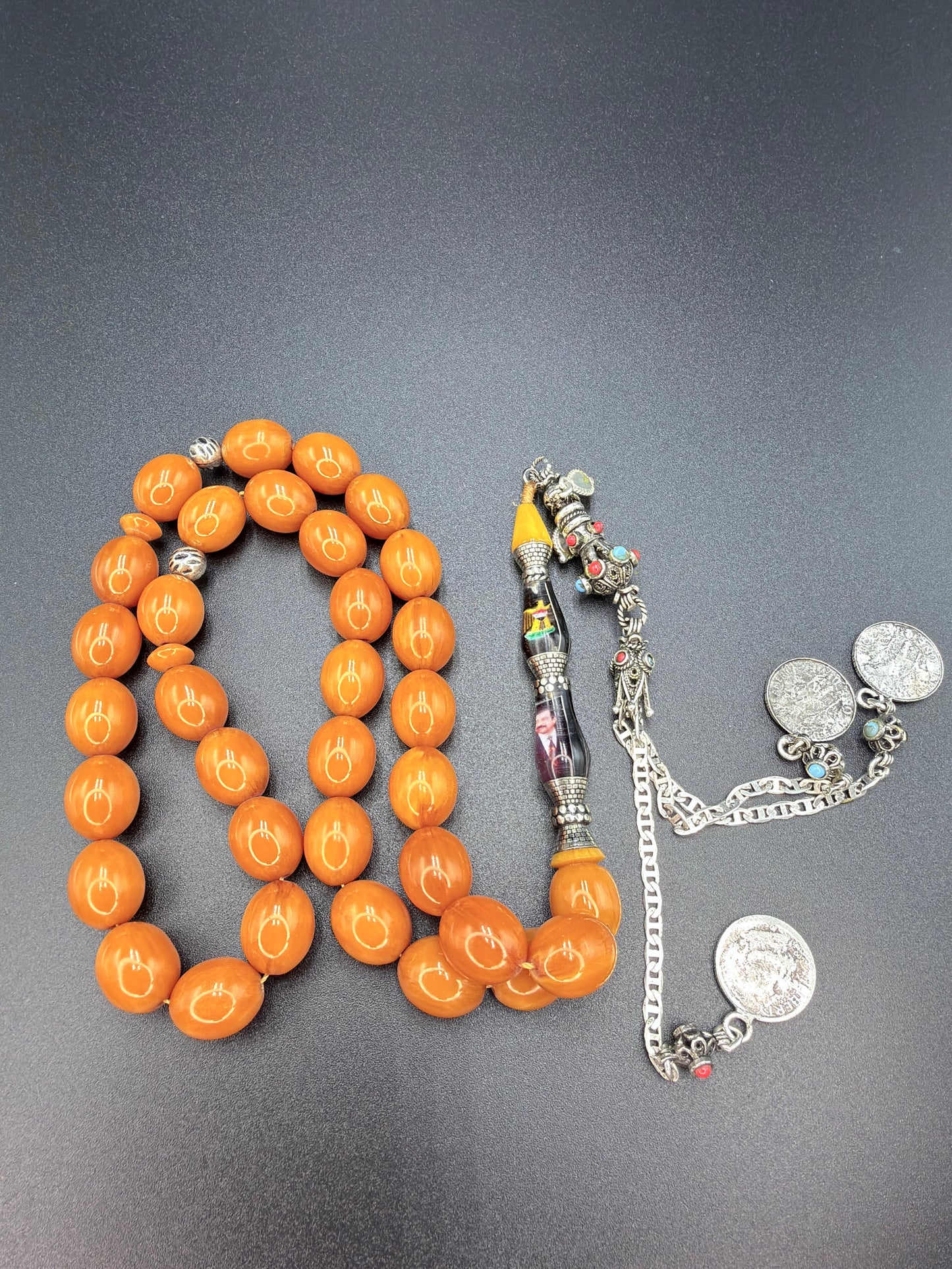 Unique musk Misbaha featuring the image of Saddam Hussein and the Iraqi national anthem, paired with a 500-grade silver tassel. مسباح مسكي مميّز يحمل صورة صدام حسين والسلام الجمهوري، مرفق بشرّابة فضّة عيار 500