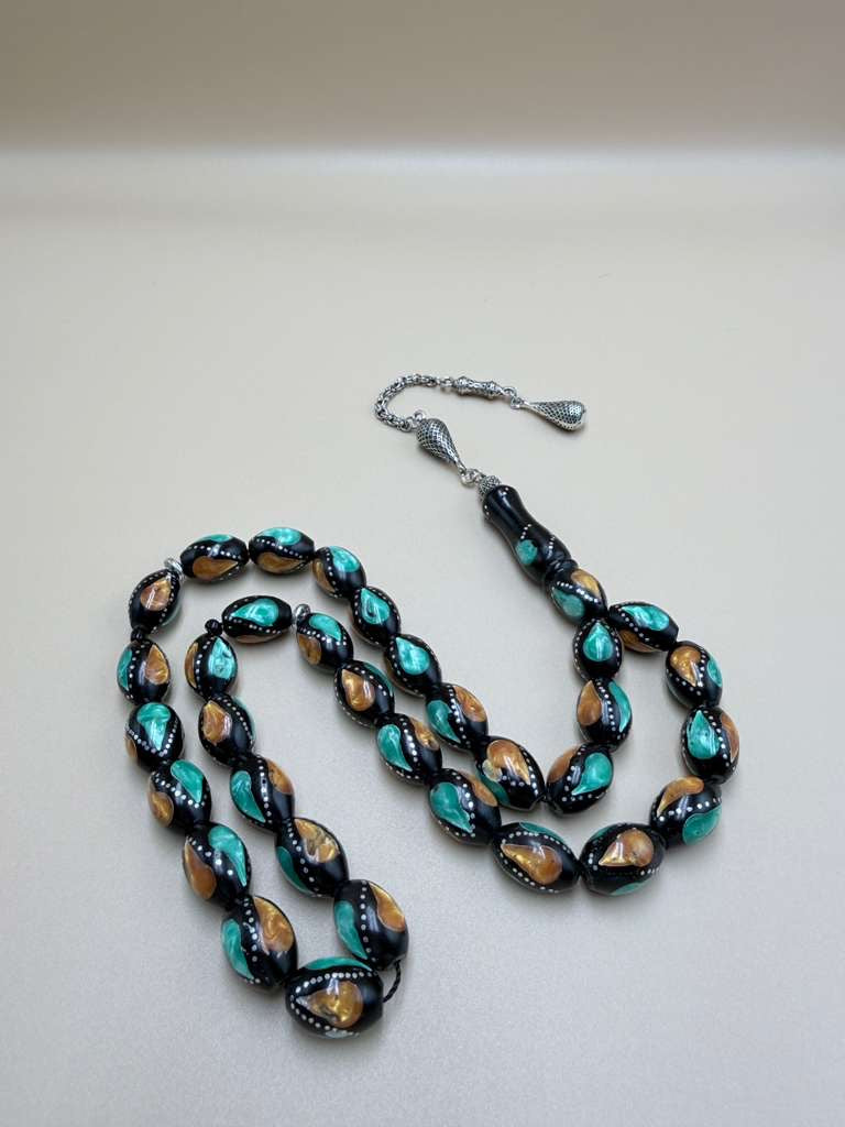 مسباح كوك، مطعّم بطحين الكهرمان وحجر المالاكيت والفضة. Kuka Wood Misbah, Inlaid with Amber Powder, Malachite Stone, and Silver.