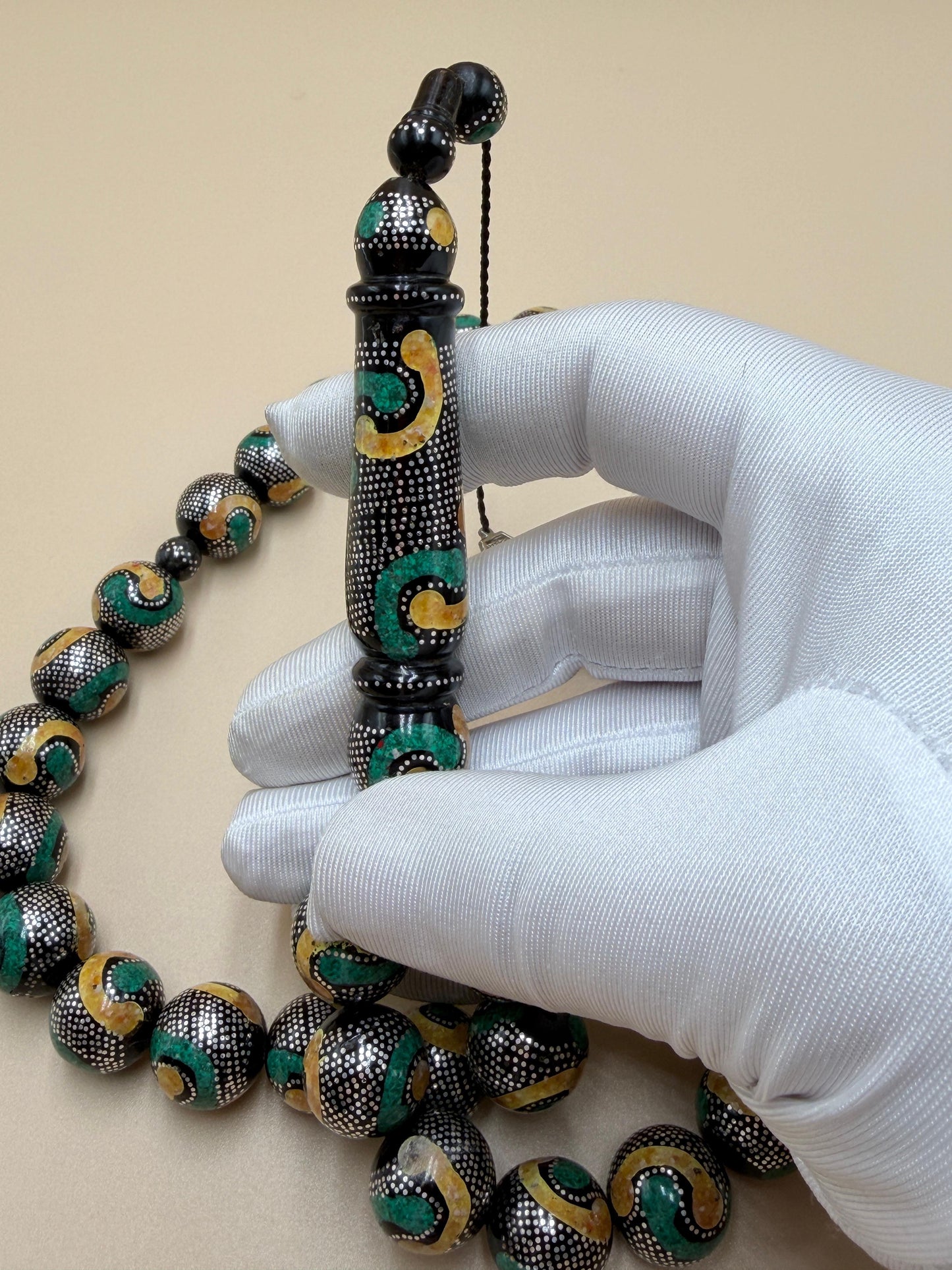 يسر بحر أحمر، مطعّم بالفضّة الخالصة عيار 925، ومزيّن بـ الكهرمان الطبيعي والملاكيت.
Red Sea Yusr, inlaid with 925 sterling silver, adorned with natural amber and malachite.