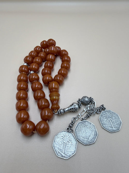 مسباح مسكي قديم، عرق أحمر، مع شرابة مميزة مزخرفة بالعملة العراقية القديمة وشرابة فضة عيار 500.