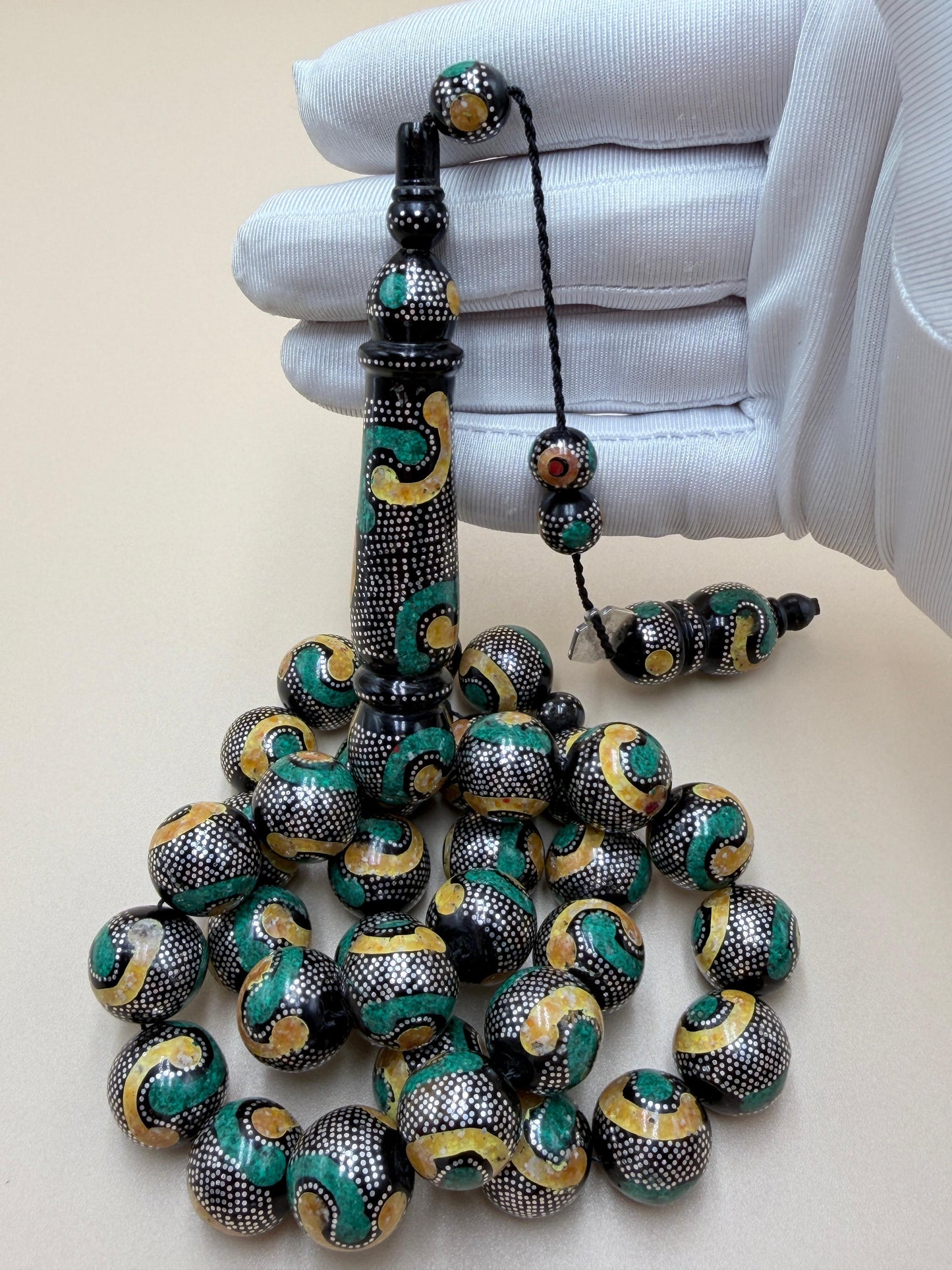 يسر بحر أحمر، مطعّم بالفضّة الخالصة عيار 925، ومزيّن بـ الكهرمان الطبيعي والملاكيت.
Red Sea Yusr, inlaid with 925 sterling silver, adorned with natural amber and malachite.