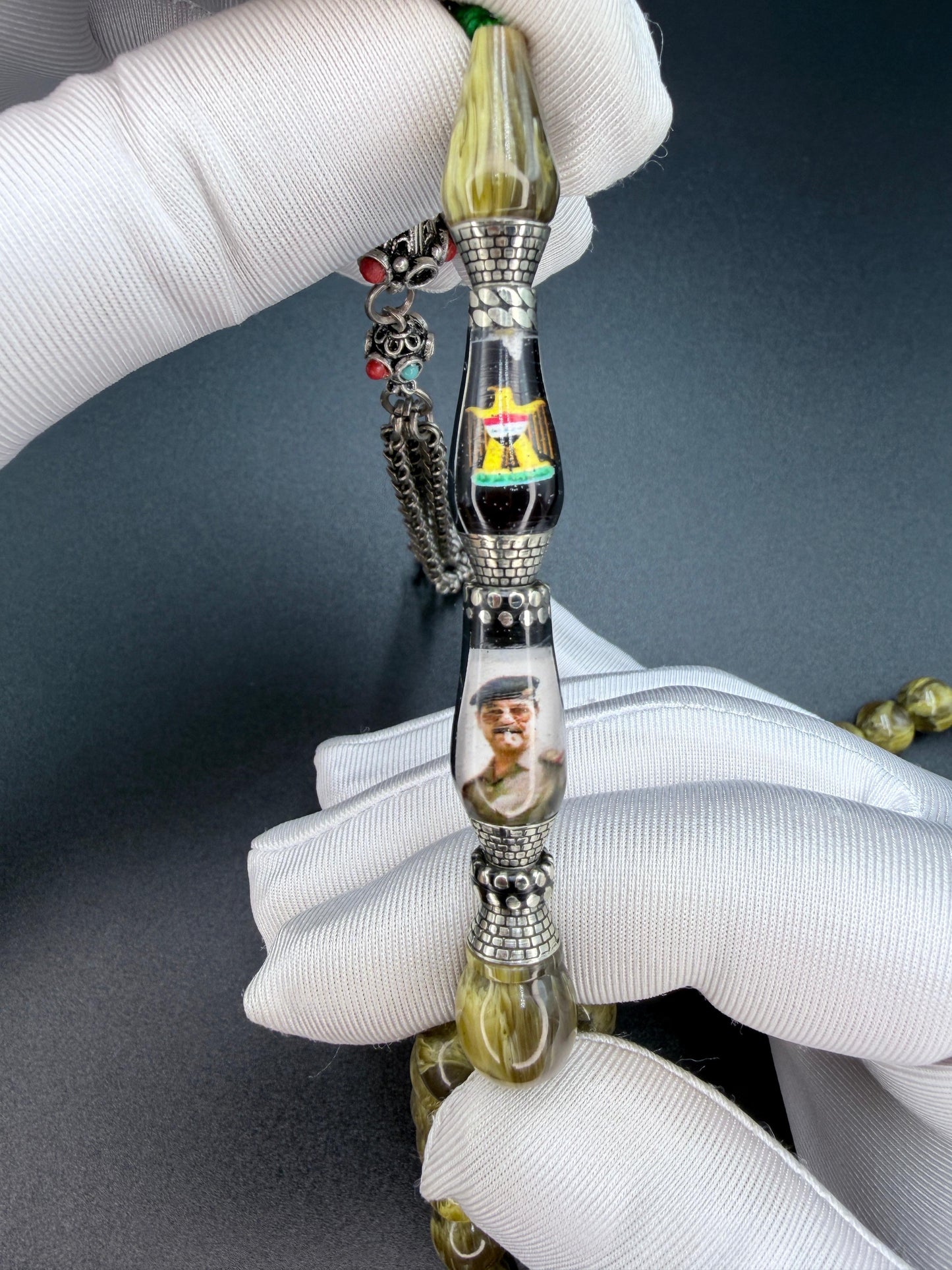 Unique musk Misbaha featuring the image of Saddam Hussein and the Iraqi national anthem, paired with a 500-grade silver tassel. مسباح مسكي مميّز يحمل صورة صدام حسين والسلام الجمهوري، مرفق بشرّابة فضّة عيار 500
