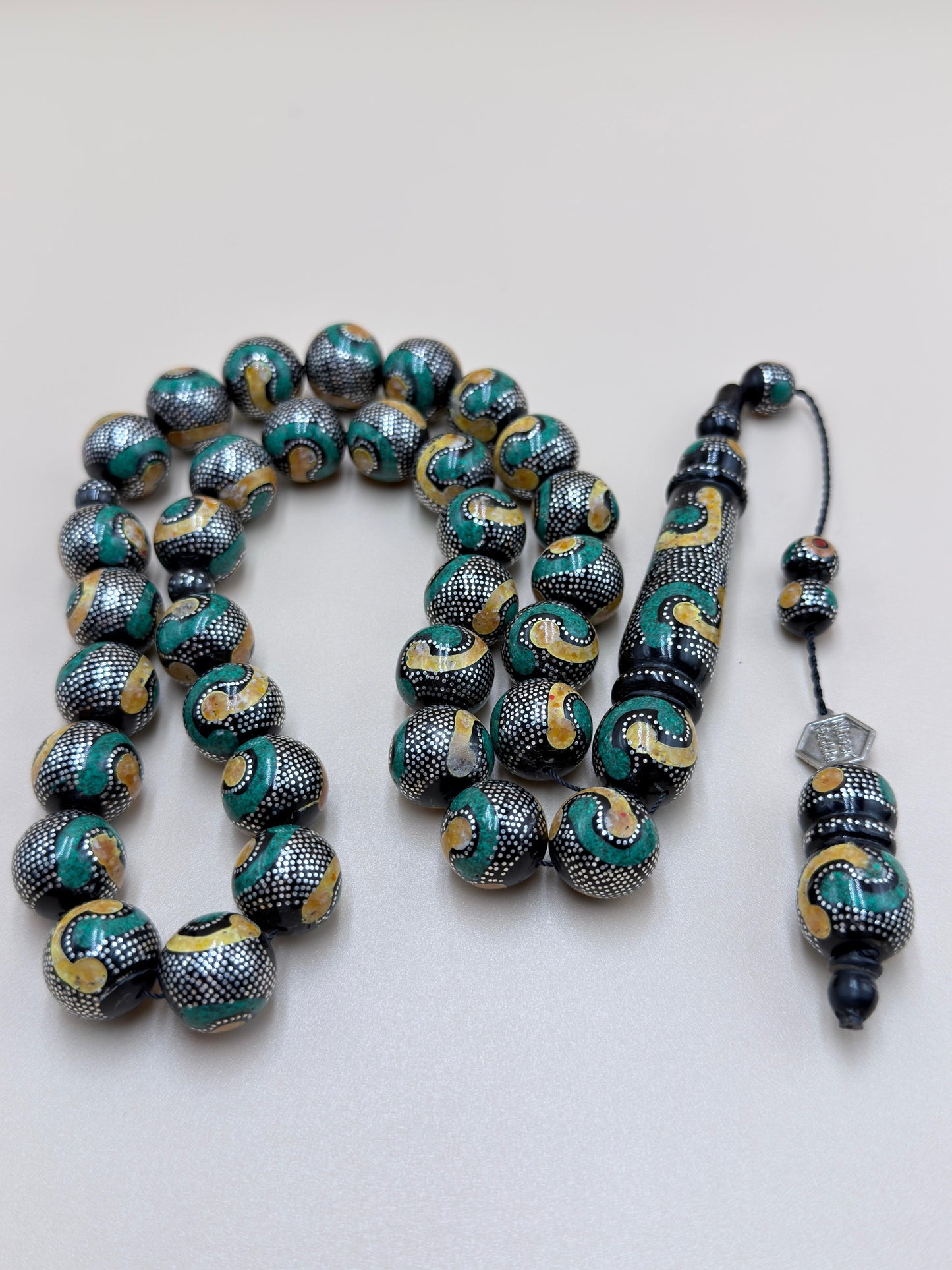 يسر بحر أحمر، مطعّم بالفضّة الخالصة عيار 925، ومزيّن بـ الكهرمان الطبيعي والملاكيت.
Red Sea Yusr, inlaid with 925 sterling silver, adorned with natural amber and malachite.