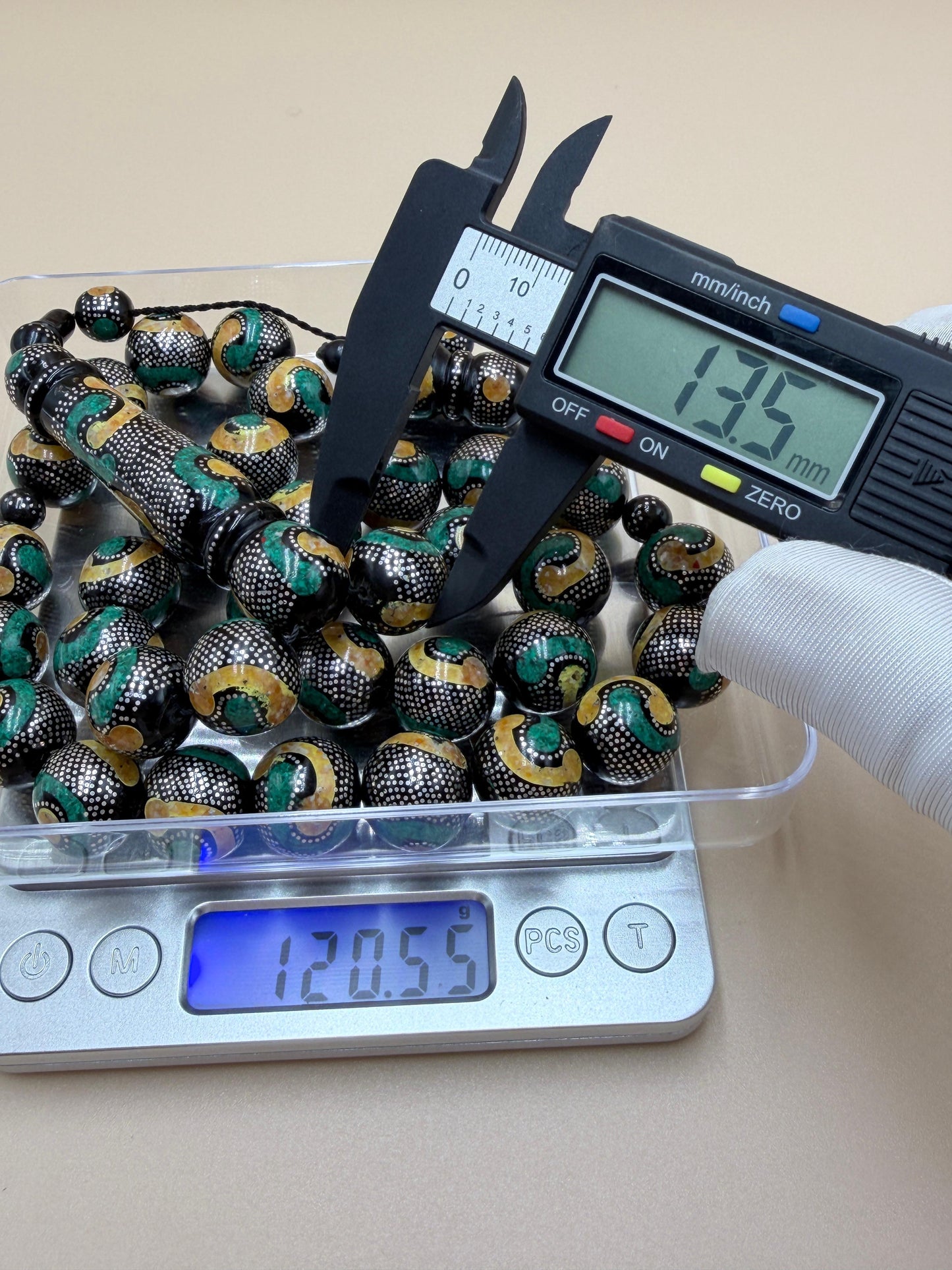 يسر بحر أحمر، مطعّم بالفضّة الخالصة عيار 925، ومزيّن بـ الكهرمان الطبيعي والملاكيت.
Red Sea Yusr, inlaid with 925 sterling silver, adorned with natural amber and malachite.