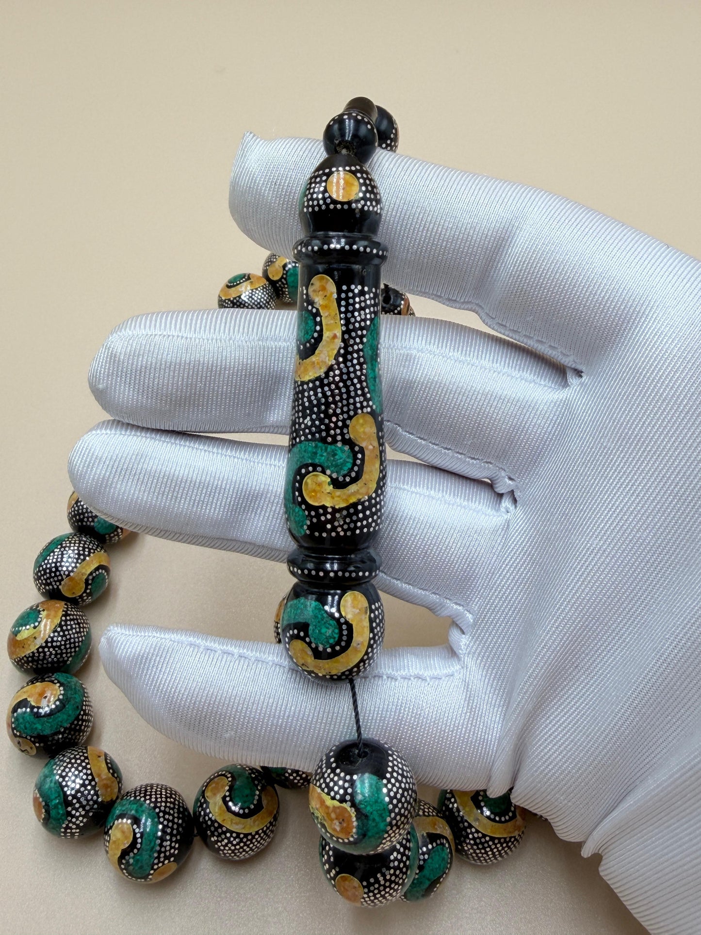 يسر بحر أحمر، مطعّم بالفضّة الخالصة عيار 925، ومزيّن بـ الكهرمان الطبيعي والملاكيت.
Red Sea Yusr, inlaid with 925 sterling silver, adorned with natural amber and malachite.