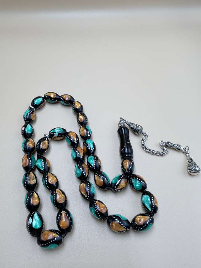 مسباح كوك، مطعّم بطحين الكهرمان وحجر المالاكيت والفضة. Kuka Wood Misbah, Inlaid with Amber Powder, Malachite Stone, and Silver.