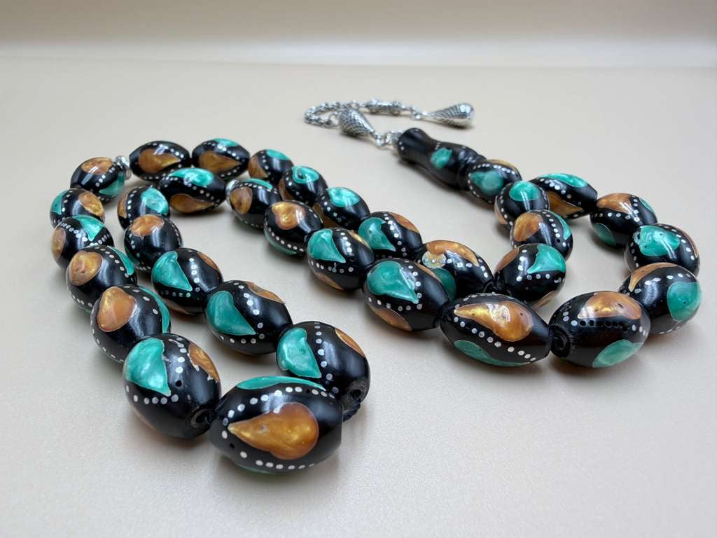 مسباح كوك، مطعّم بطحين الكهرمان وحجر المالاكيت والفضة. Kuka Wood Misbah, Inlaid with Amber Powder, Malachite Stone, and Silver.