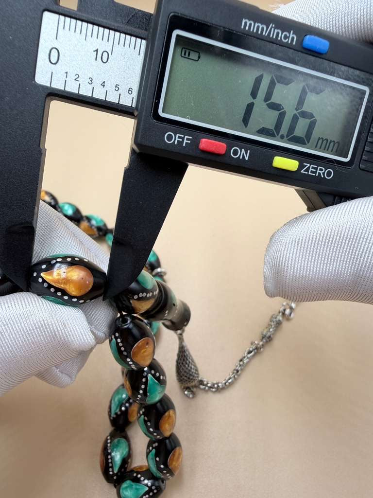 مسباح كوك، مطعّم بطحين الكهرمان وحجر المالاكيت والفضة. Kuka Wood Misbah, Inlaid with Amber Powder, Malachite Stone, and Silver.