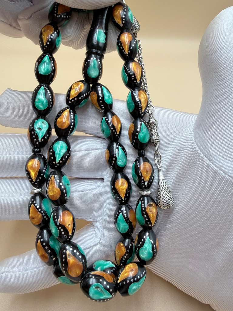 مسباح كوك، مطعّم بطحين الكهرمان وحجر المالاكيت والفضة. Kuka Wood Misbah, Inlaid with Amber Powder, Malachite Stone, and Silver.