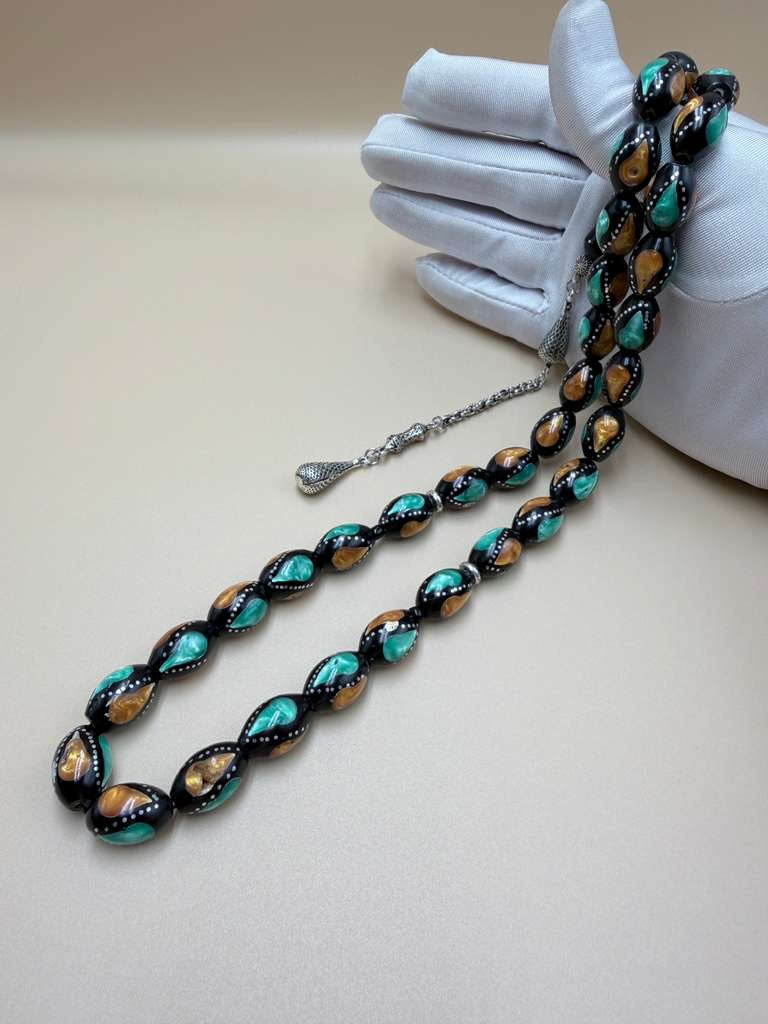 مسباح كوك، مطعّم بطحين الكهرمان وحجر المالاكيت والفضة. Kuka Wood Misbah, Inlaid with Amber Powder, Malachite Stone, and Silver.