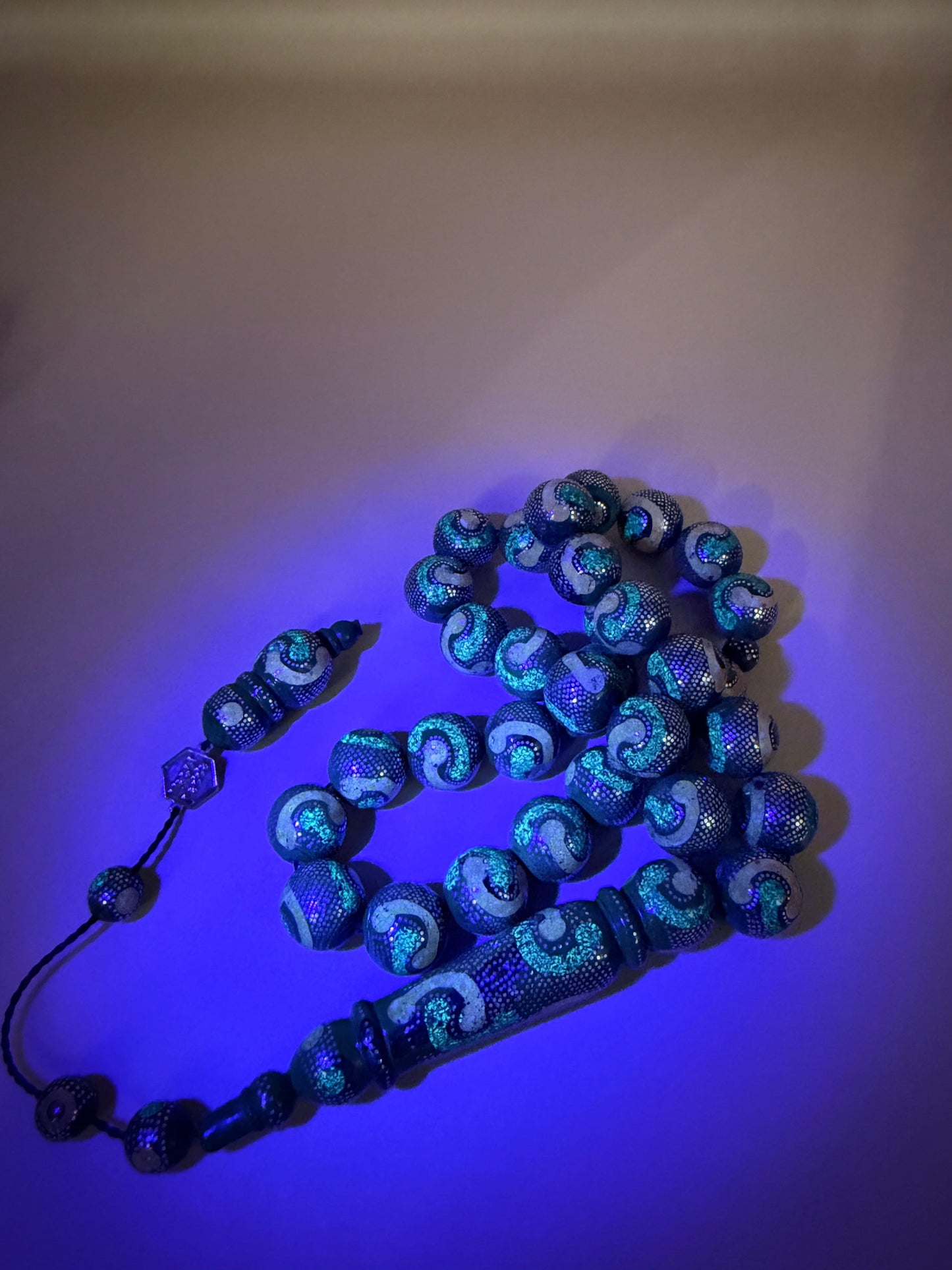 يسر بحر أحمر، مطعّم بالفضّة الخالصة عيار 925، ومزيّن بـ الكهرمان الطبيعي والملاكيت.
Red Sea Yusr, inlaid with 925 sterling silver, adorned with natural amber and malachite.