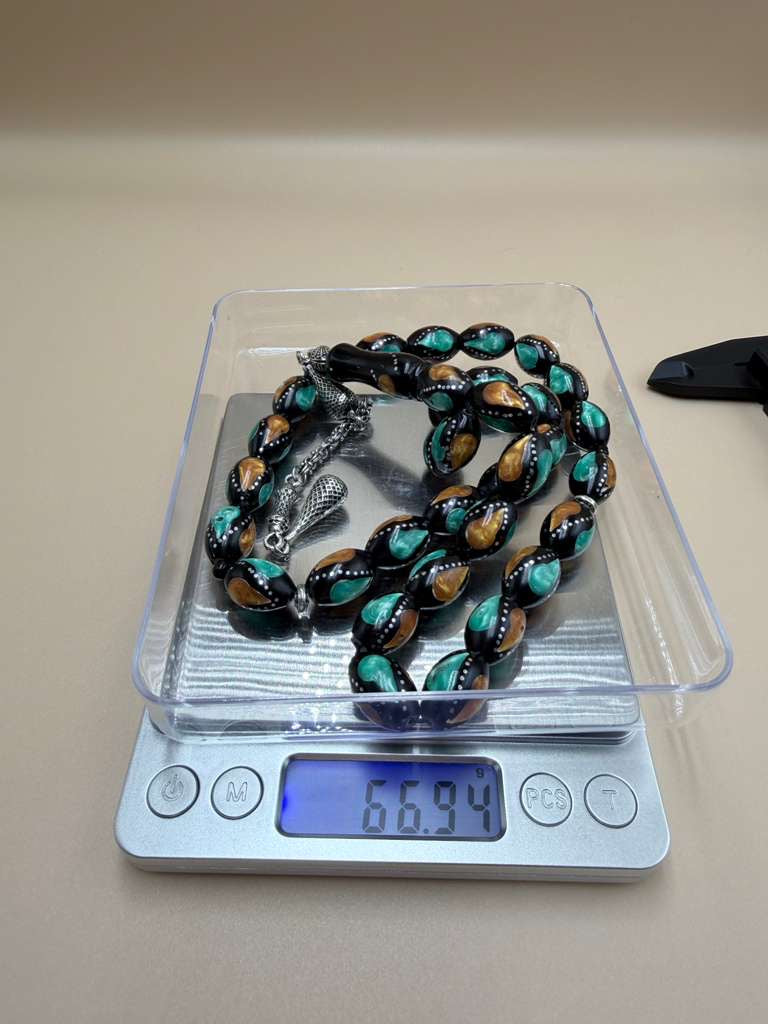 مسباح كوك، مطعّم بطحين الكهرمان وحجر المالاكيت والفضة. Kuka Wood Misbah, Inlaid with Amber Powder, Malachite Stone, and Silver.