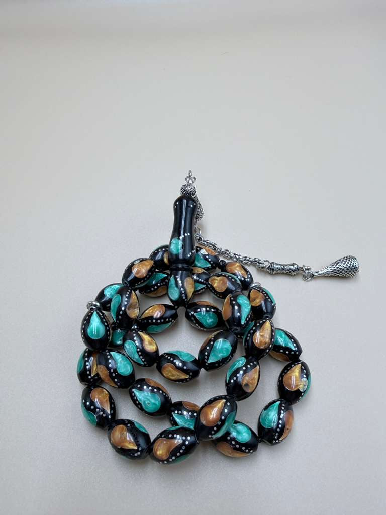 مسباح كوك، مطعّم بطحين الكهرمان وحجر المالاكيت والفضة. Kuka Wood Misbah, Inlaid with Amber Powder, Malachite Stone, and Silver.